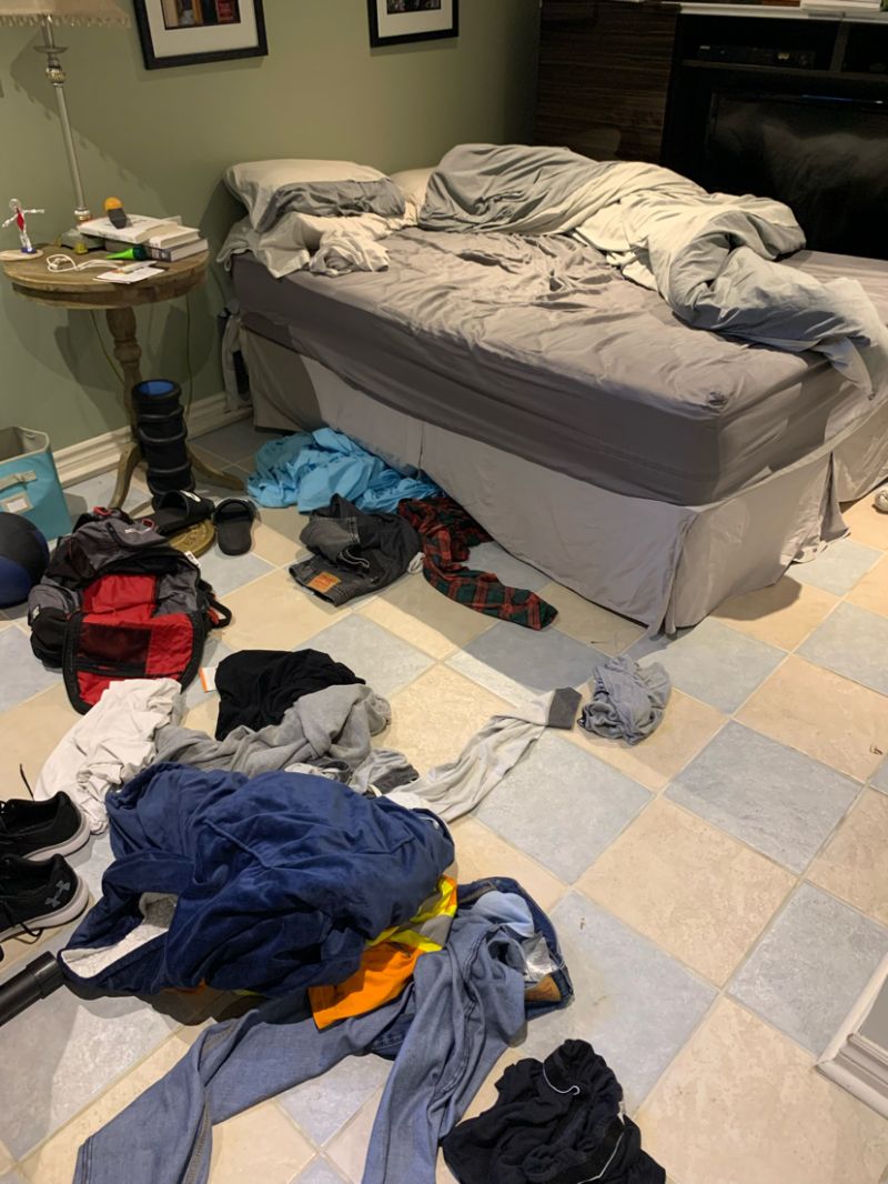 an unmade bed with clothes on the floor